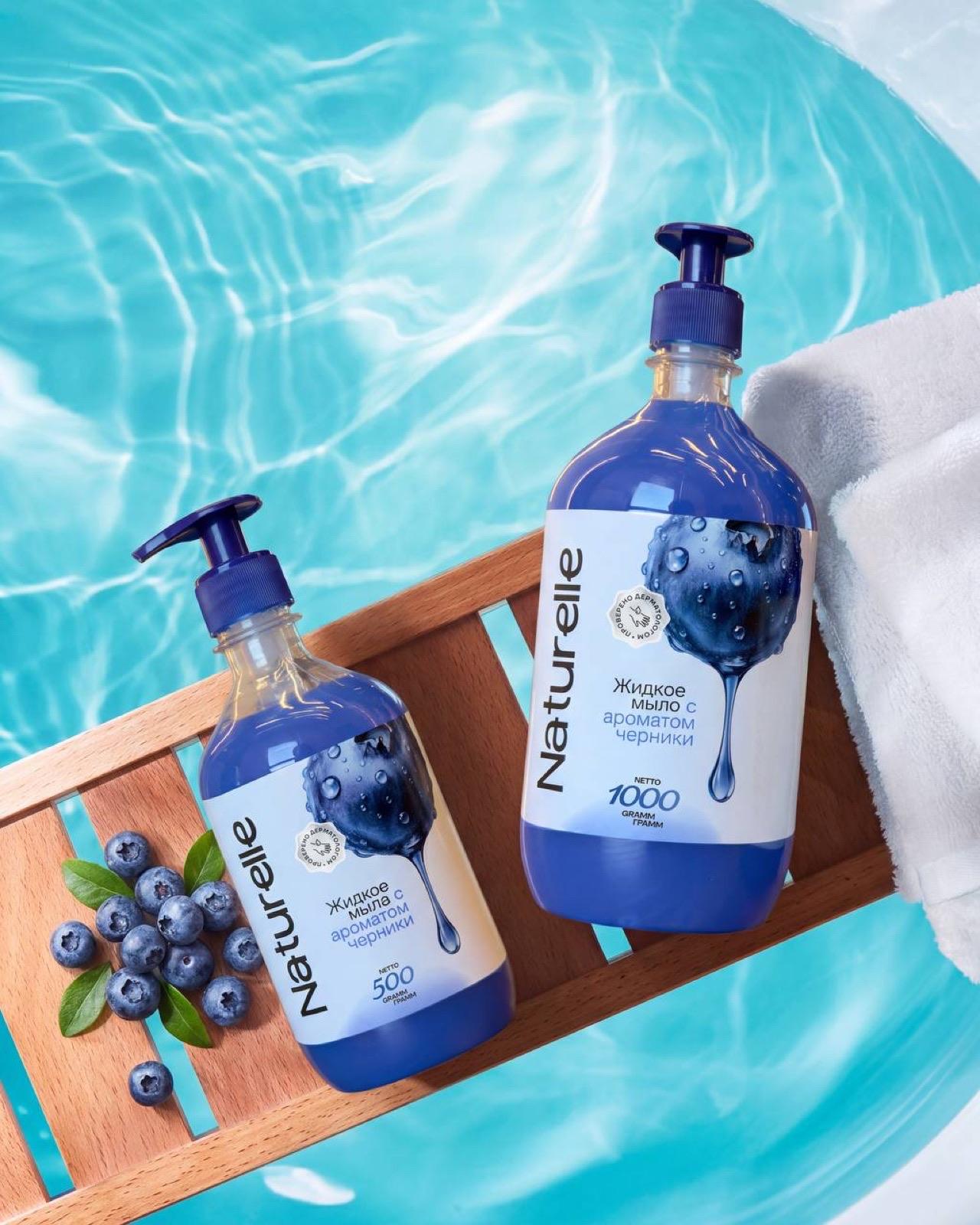 Naturelle blueberry hand soap — bottles on a wooden bath tray over pool water