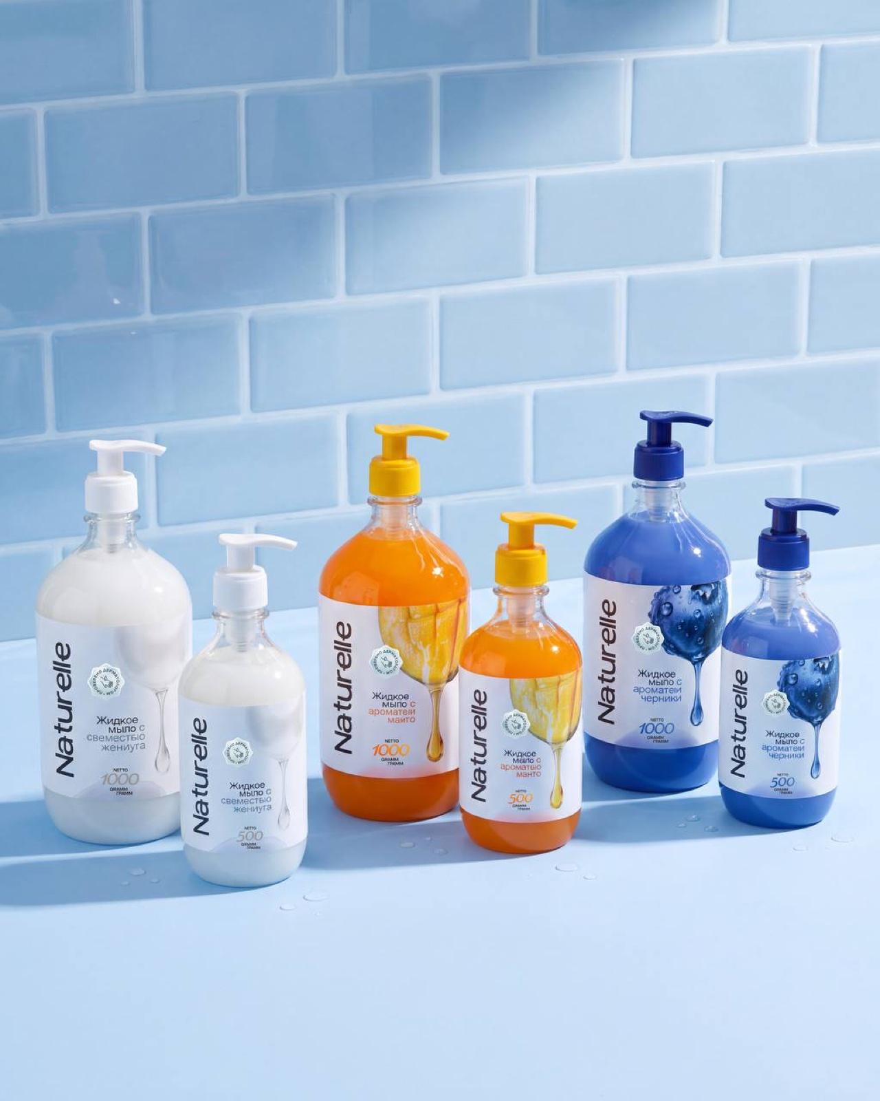 Full Naturelle range — pearl, mango, and blueberry hand soap bottles on a blue tile bathroom shelf